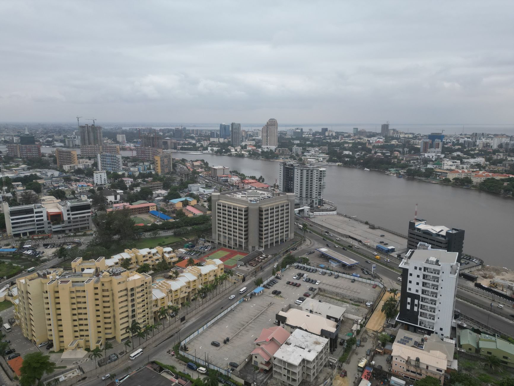 Aerial shot capturing Lagos cityscape with modern buildings by Lagos Lagoon under an overcast sky.